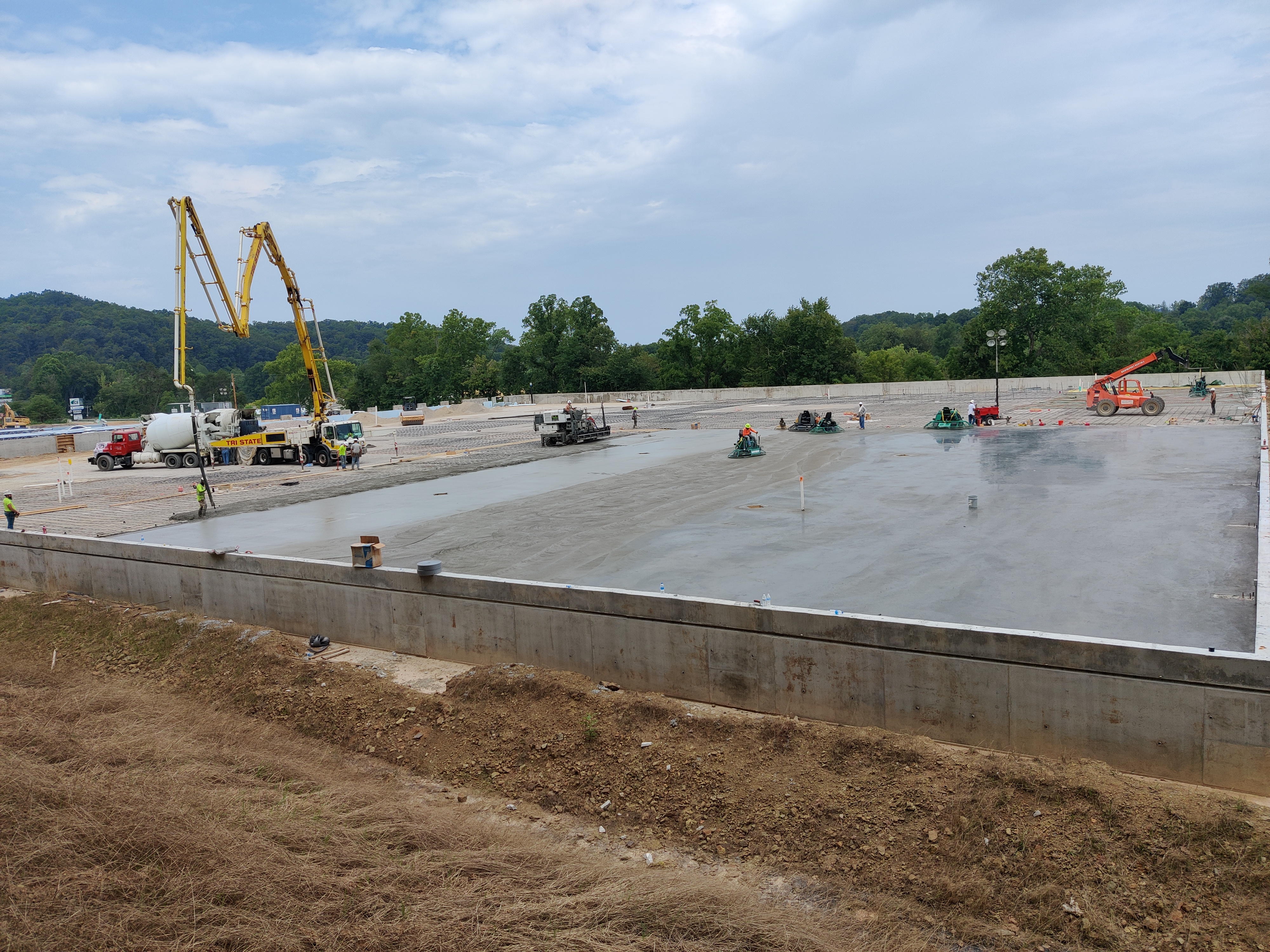 Wide commercial slab formed and prepared with a boom pump set up alongside, ready for laser screeding
