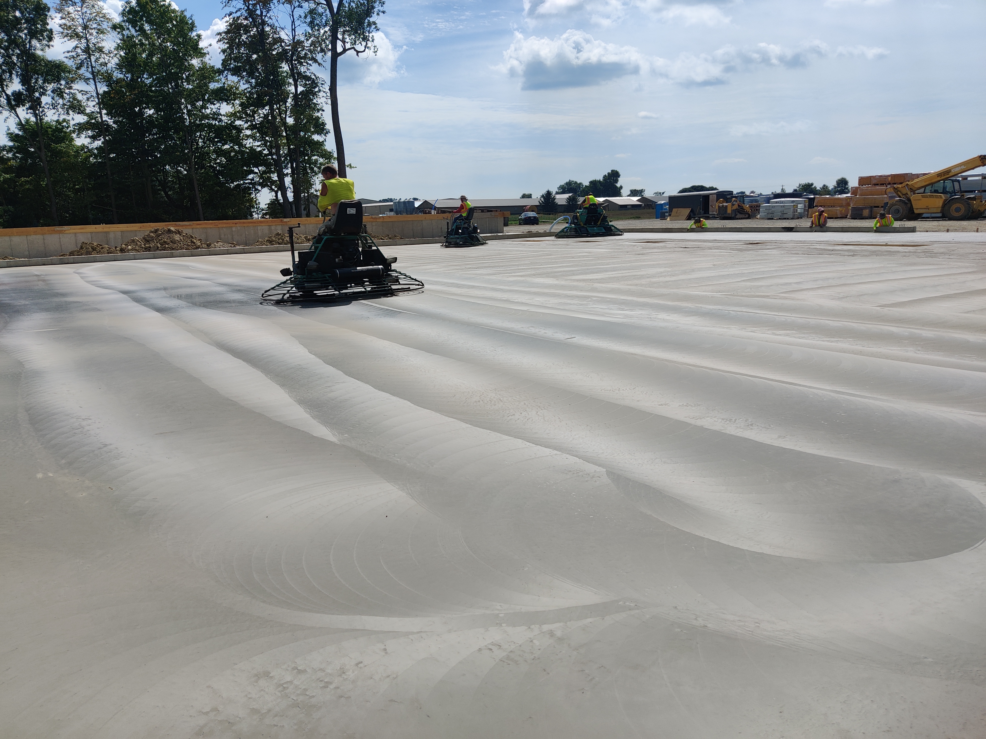 Ride-on power trowel finishing a large commercial warehouse concrete slab