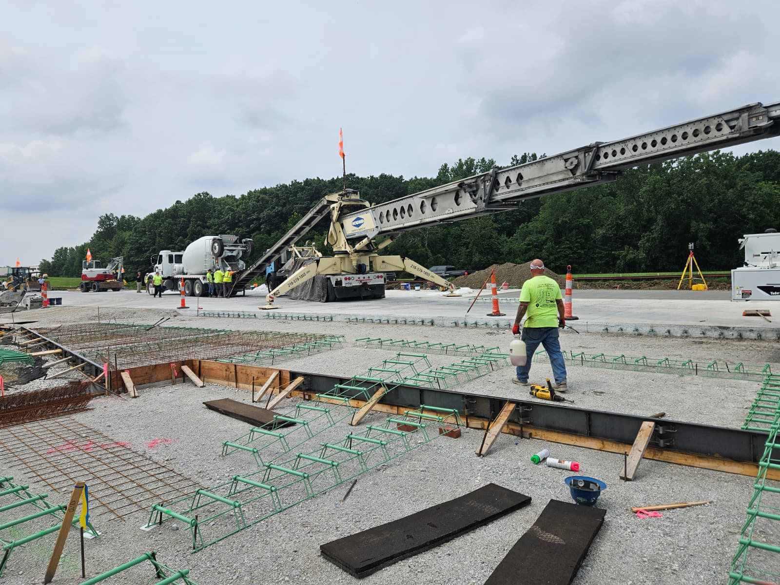 Truck-mounted placing conveyor and crew preparing an airfield slab pour
