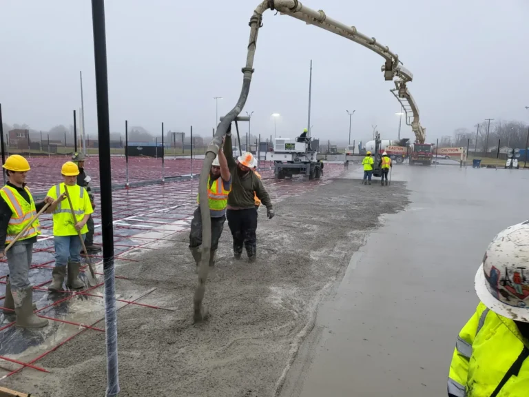 Crew placing concrete from a pump hose on a large commercial slab