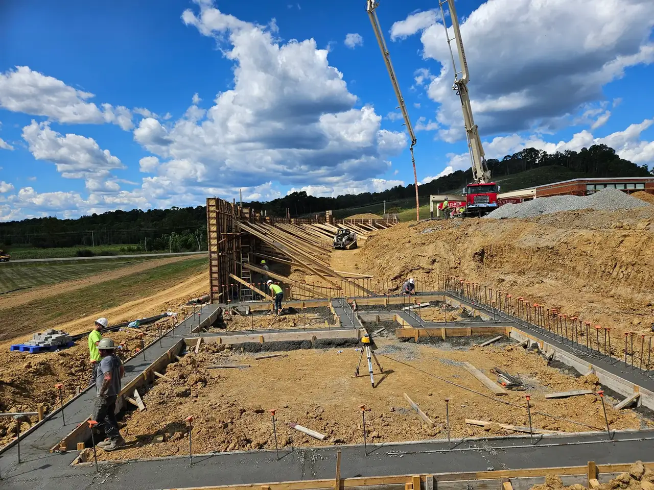 Boom pump placing concrete into formed foundation walls on a commercial site