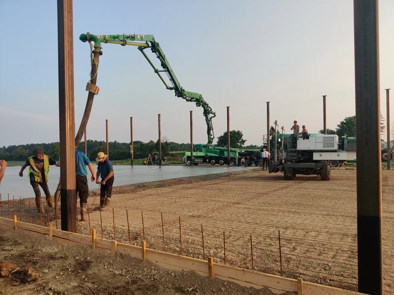 Boom pump reaching across a commercial slab with structural steel columns already erected