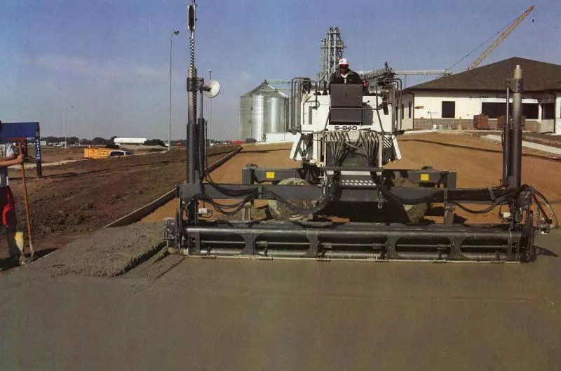 Concrete paving machine placing an agricultural pad beside grain silos in Ohio