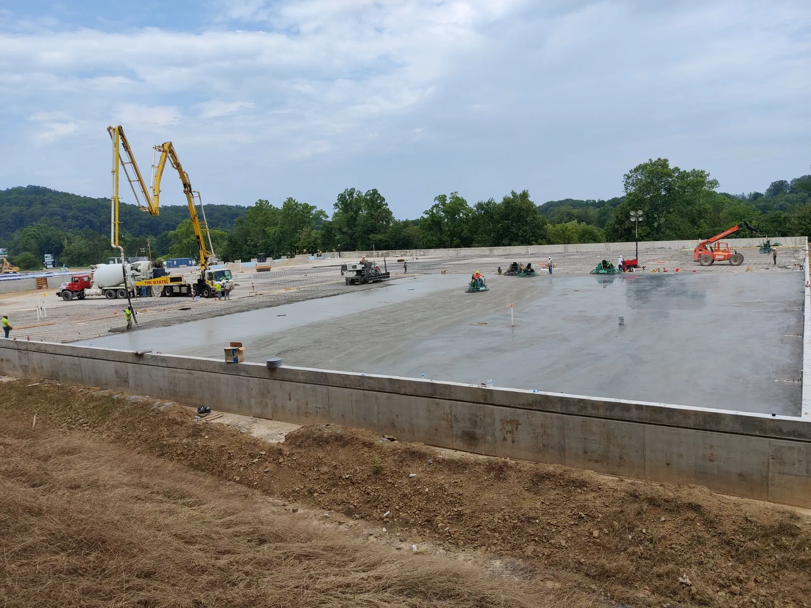 Wide commercial slab poured on a raised foundation with boom pumps on site