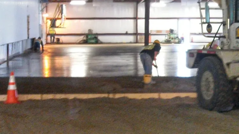 Crew finishing an interior commercial concrete floor inside a steel building